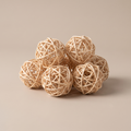Natural rattan decorative balls clustered in a pale ceramic bowl on a coffee table
