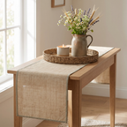 Natural linen runner with a contrast-bound edge on a light console with a woven tray, candle and wildflowers