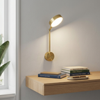 Gold wall sconce above a minimalist wooden desk providing warm reading light