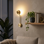 Gold wall sconce on a living room accent wall beside a floating shelf with a plant