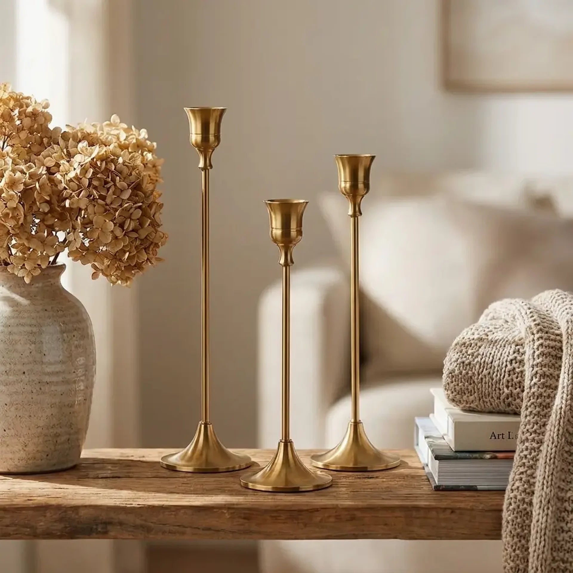 Set of three vintage tapered metal candle holders in graduated heights — styled on wooden shelf with books and throw