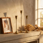 Set of three vintage tapered metal candle holders in graduated heights — on plaster fireplace mantel