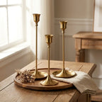 Set of three vintage tapered metal candle holders in graduated heights — on oak entryway console with brass tray