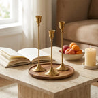 Set of three vintage tapered metal candle holders in graduated heights — on travertine coffee table