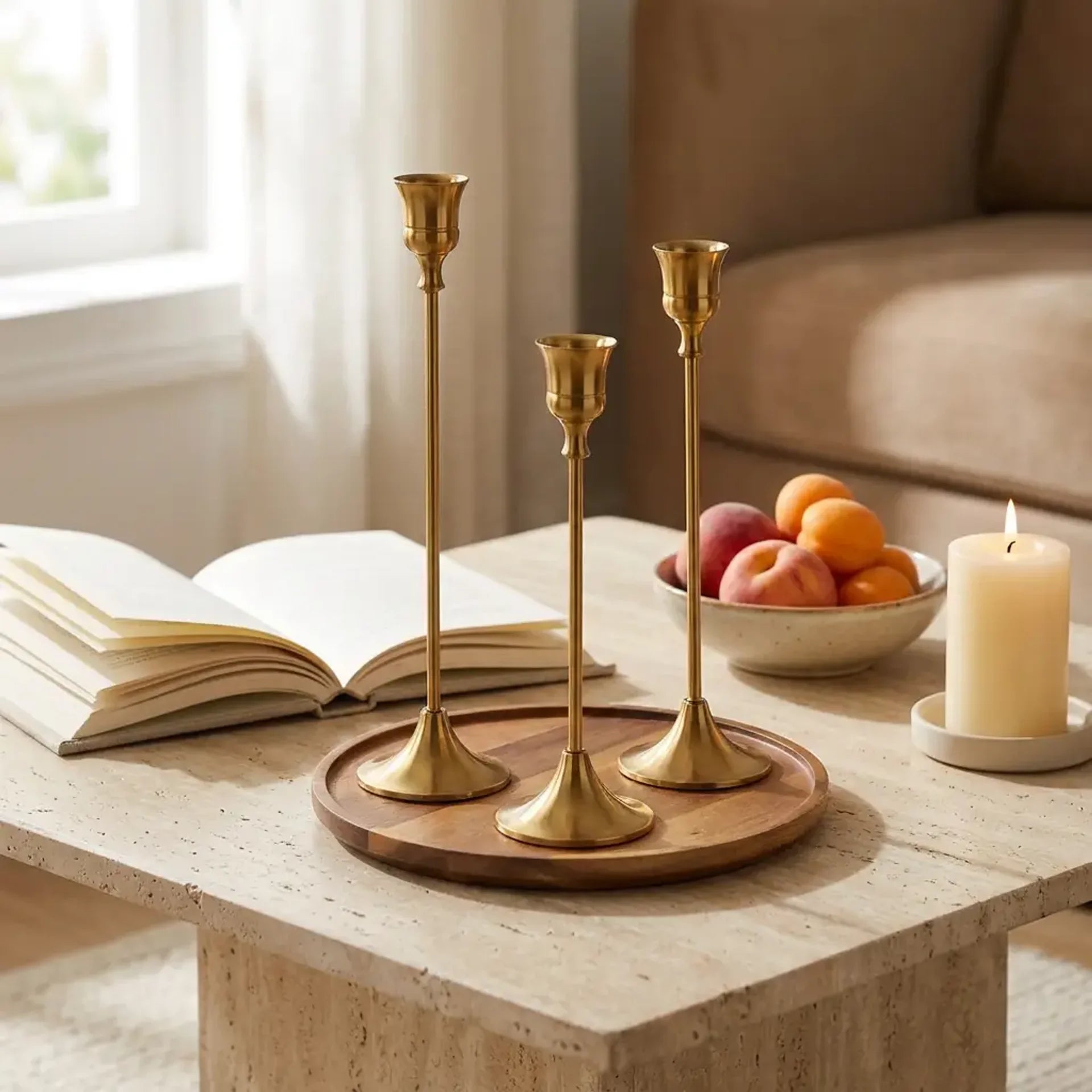 Set of three vintage tapered metal candle holders in graduated heights — on travertine coffee table