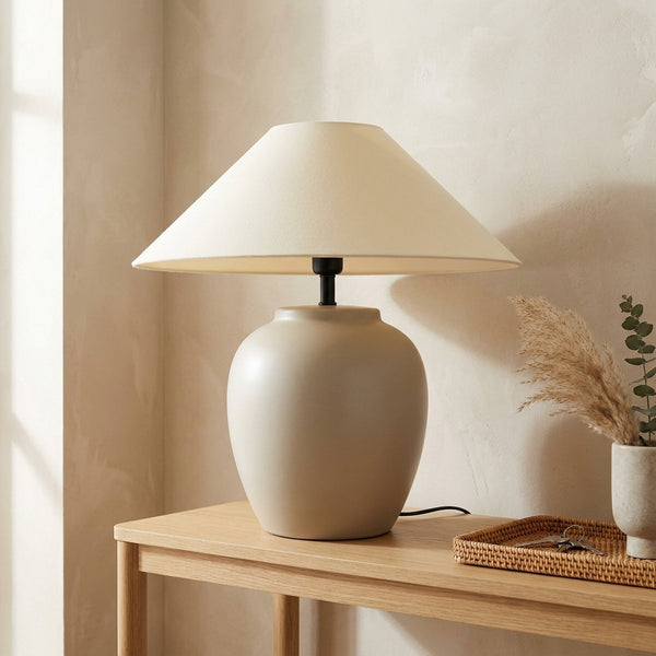 Wabi-sabi ceramic-look urn table lamp with matte oatmeal base and wide cream coolie fabric shade on a wood console.
