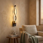 Nordic Wave LED Wall Sconce in black beside a reading chair