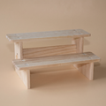 Two-step natural wood display riser on a plain studio backdrop